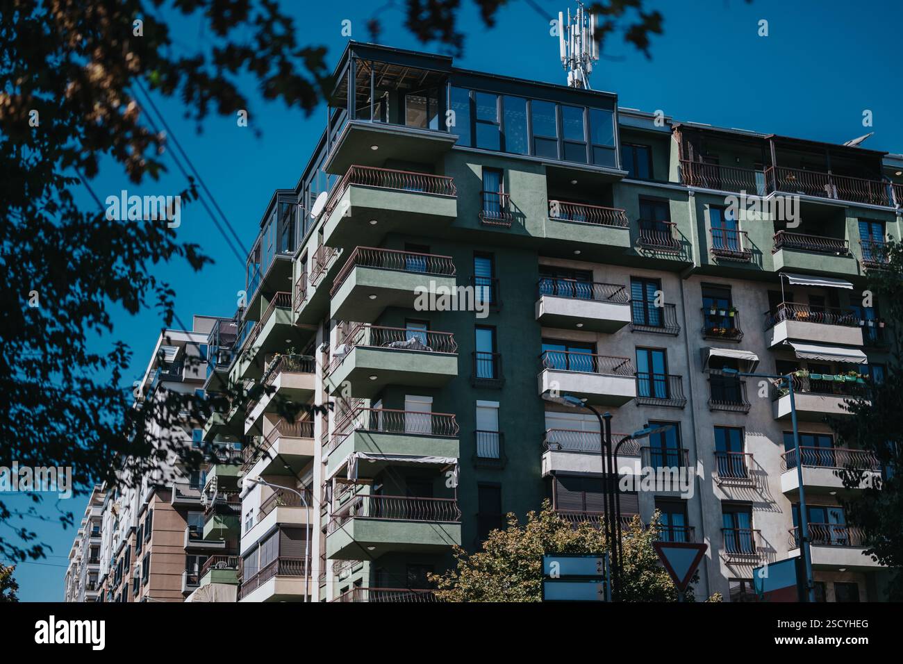 Modern apartment building with balconies and green facade under blue ...