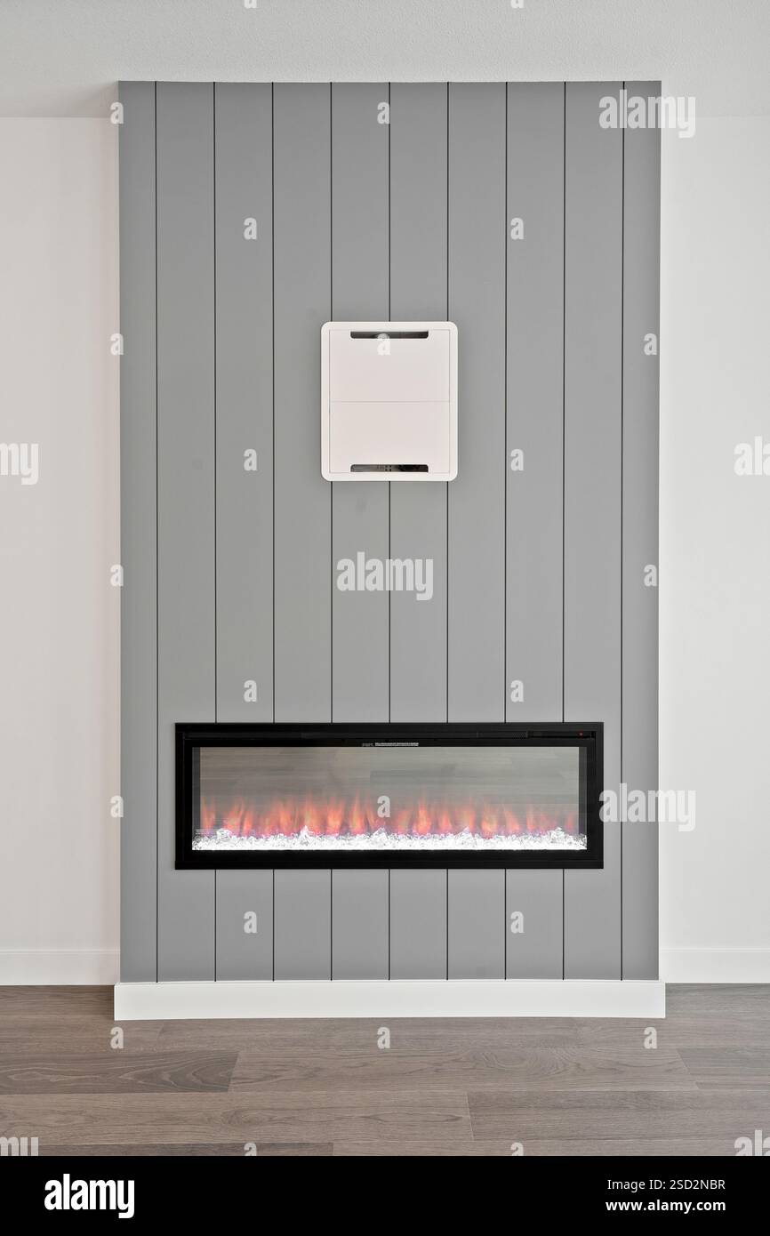 Fireplace is on a wall with a gray background. The fireplace is black and has a white mantle Stock Photo