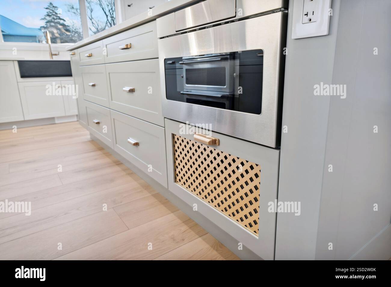 Kitchen with a silver microwave and a wooden floor. The microwave is on a counter next to a drawer Stock Photo