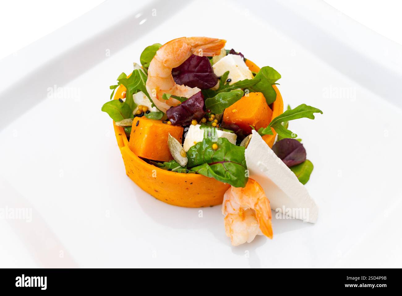 A vibrant salad featuring fresh shrimp, mixed greens, and diced vegetables served in a circular composition. Ideal for a light lunch or healthy option Stock Photo
