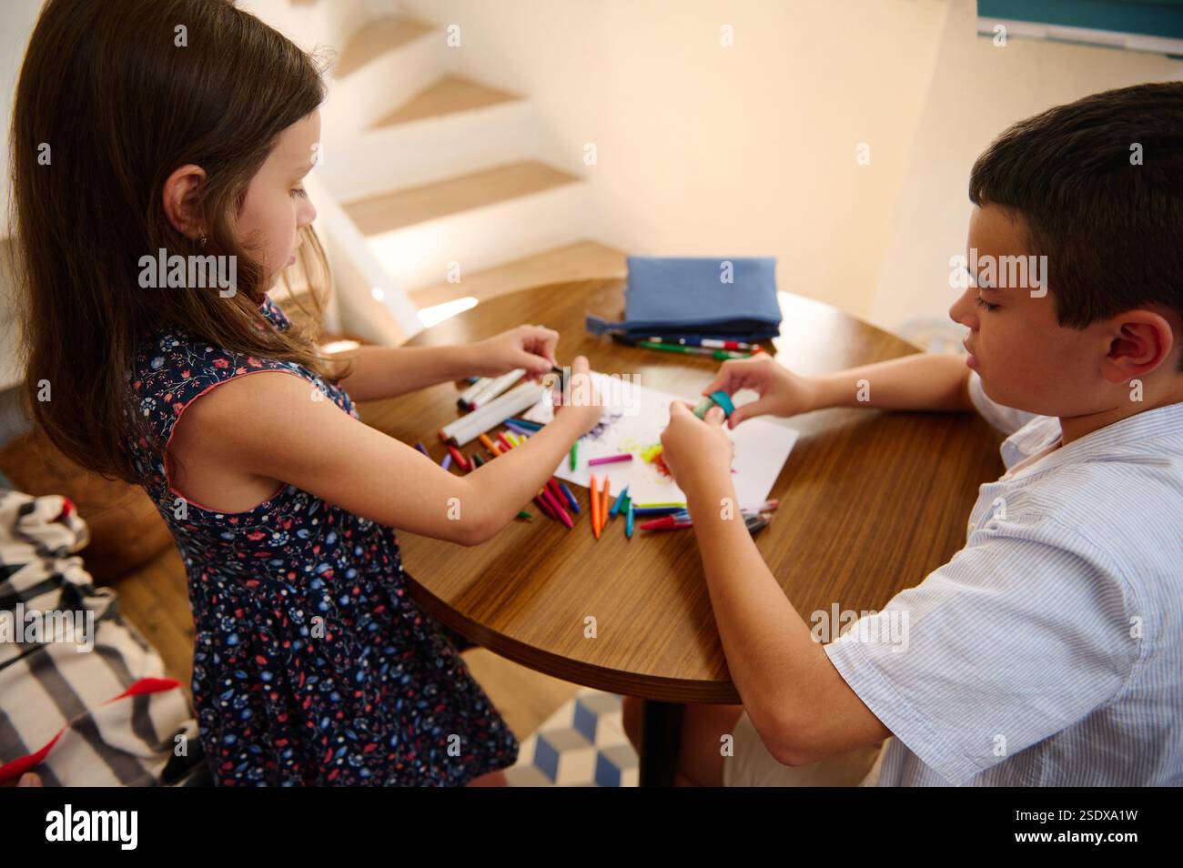 Two children engaged in drawing and coloring at a table in a cozy ...