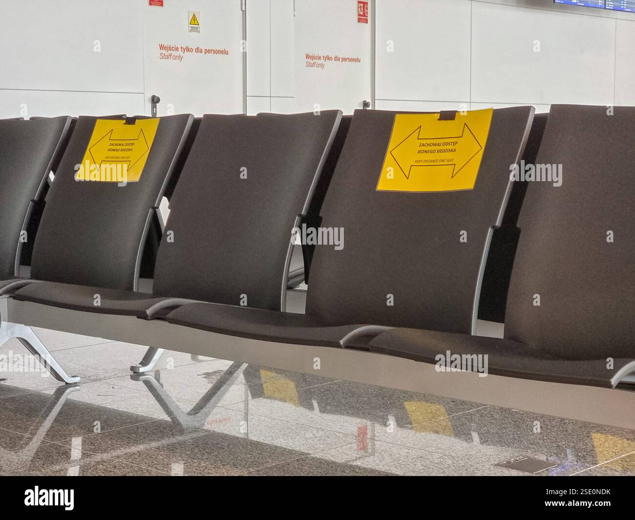 Close-up of empty chairs in airport terminal during COVID-19 pandemic with signs telling that alternate seats should be unoccupied to keep distance - Smartphone Captured Stock Image