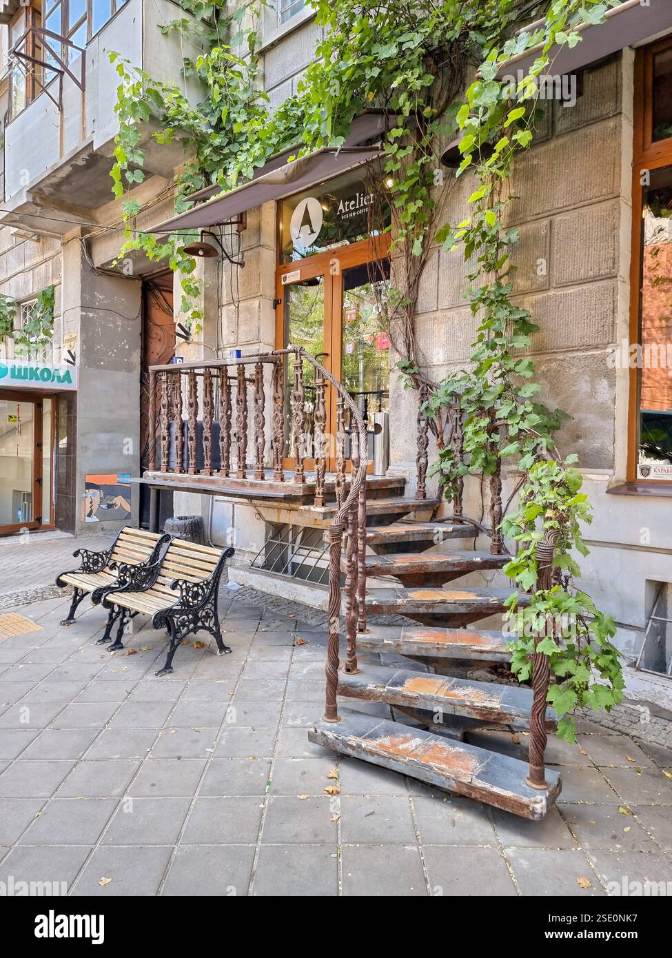 Idyllic romantic street view: wooden benches in front of historical curved stairs to coffee shop Cafe 'Atelier' in Odesa / Odessa, Ukraine - Smartphone Captured Stock Image
