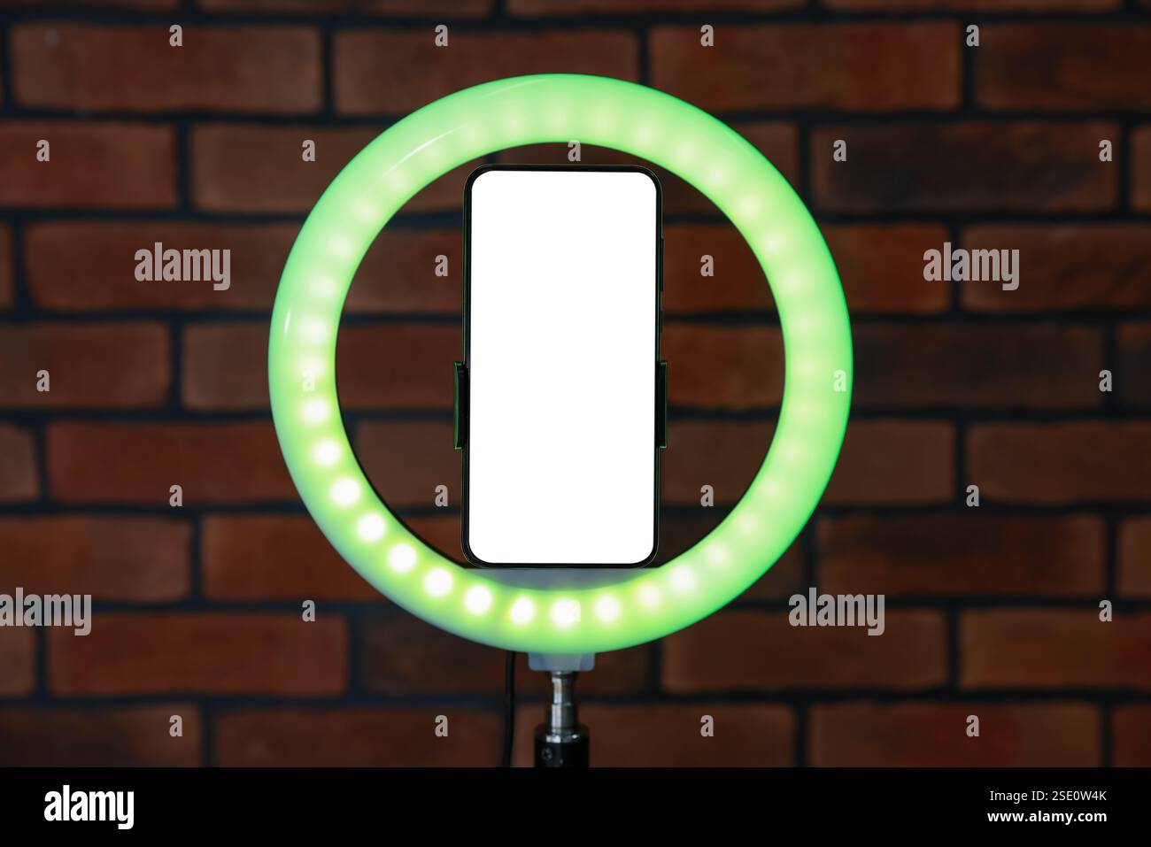 Ring lamp with smartphone against brick wall Stock Photo