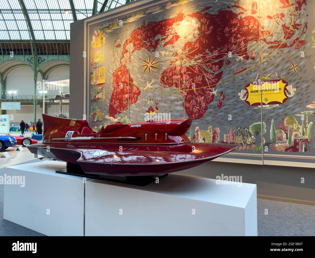 Classic racing boat displayed in an art gallery alongside historic maps ...