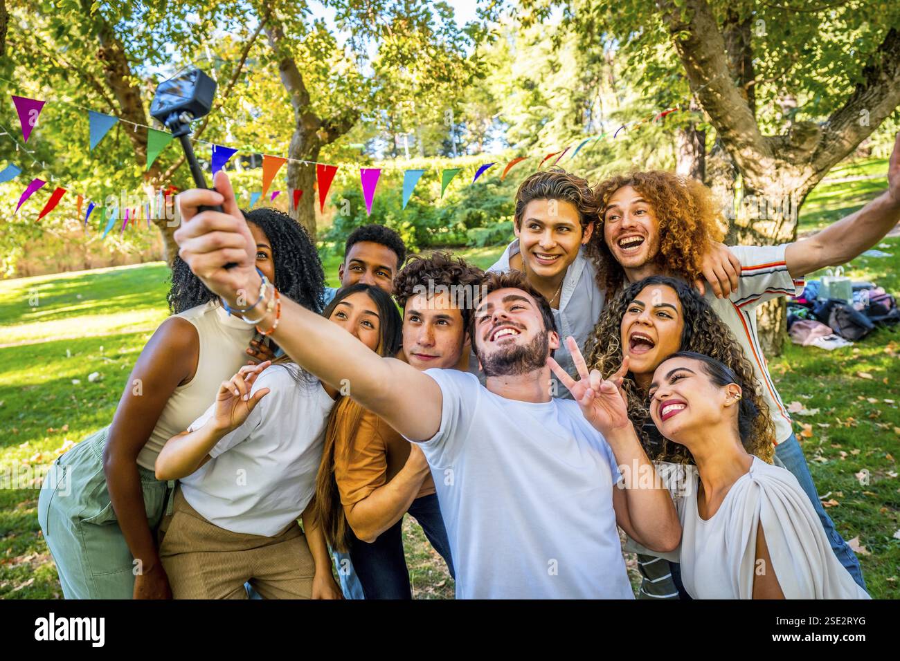 Cool multi-ethnic friends gesturing happily taking selfie in a park ...