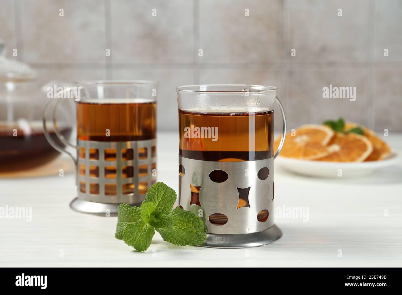Glasses of tea in metal holders served on white wooden table, closeup Stock Photo
