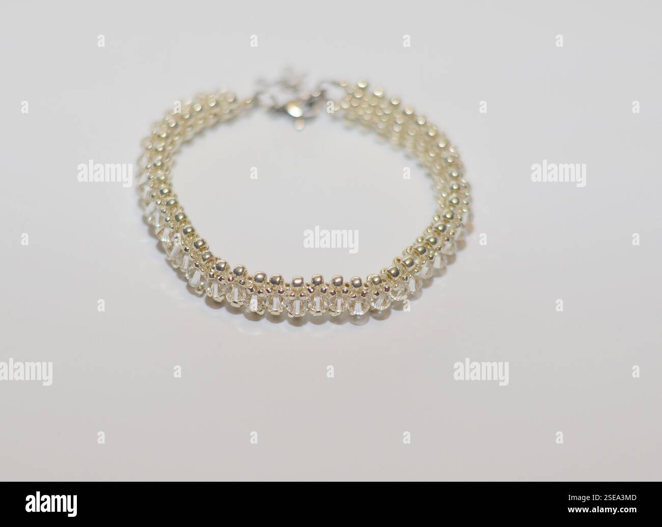 Elegant handmade beaded bracelet with clear crystal and silver beads, creating a sophisticated and delicate design, displayed on a white background Stock Photo