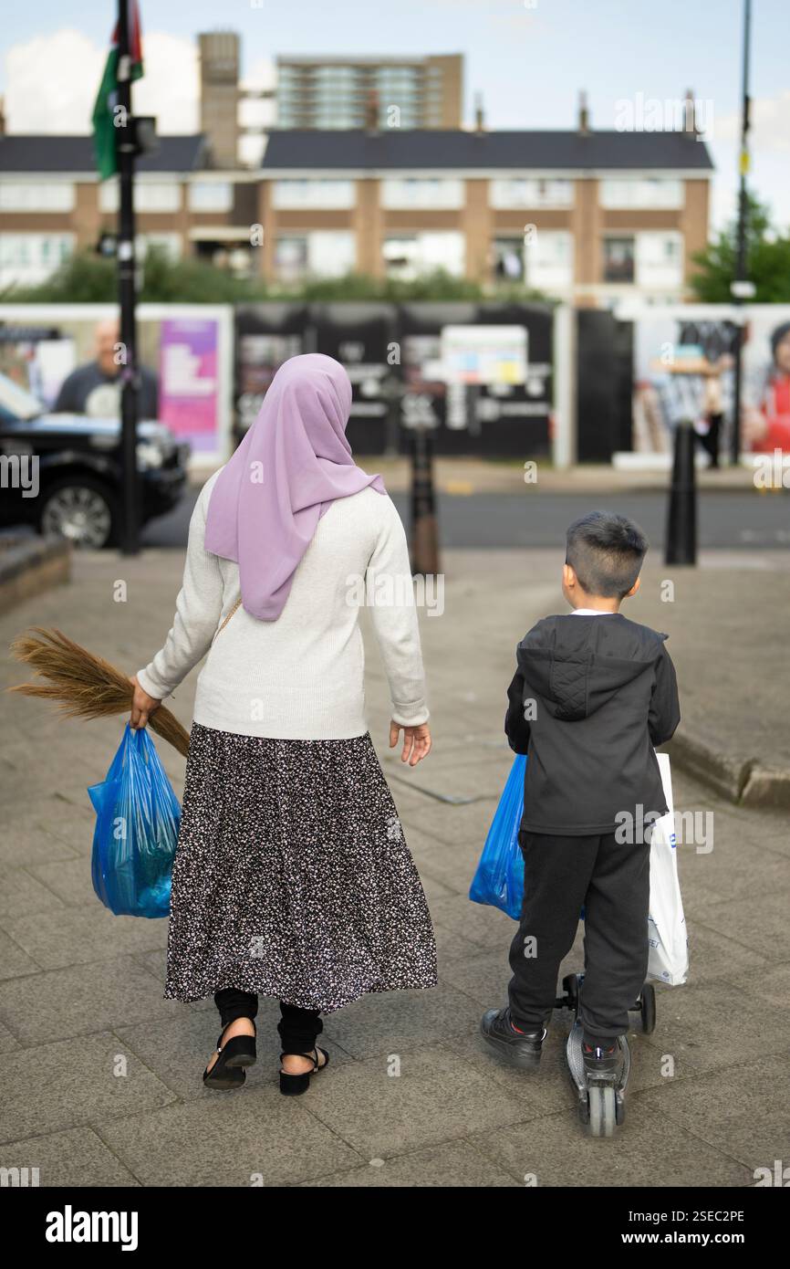 Woman in hijab and child with scooter, likely shopping,  Chrisp Street, Poplar, East London Stock Photo
