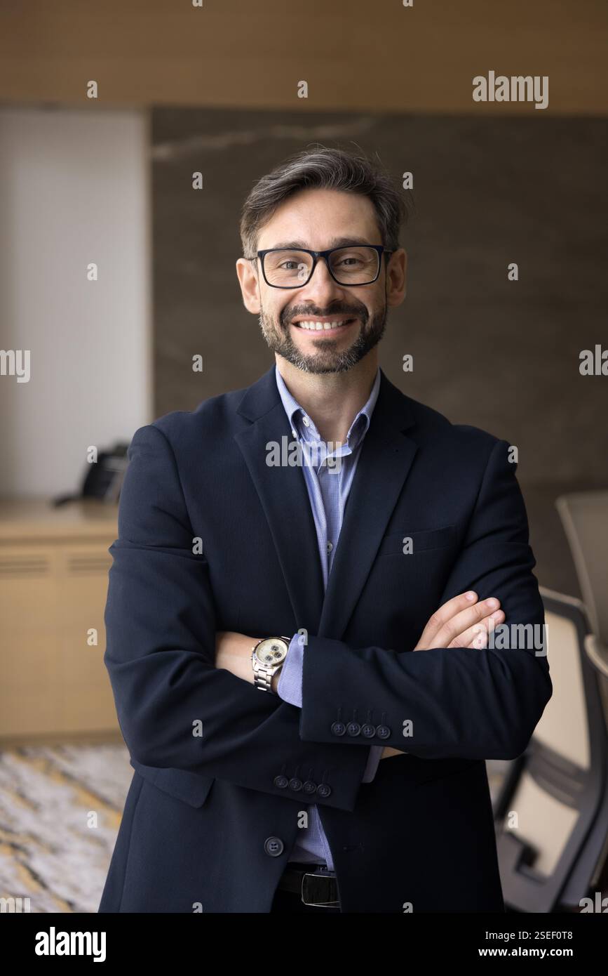 Smiling businessman staring at camera standing in modern office Stock Photo