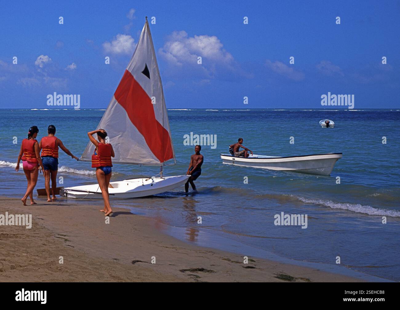 Beach, helper pulls sailboat into the water for 3 tourists, Playa ...
