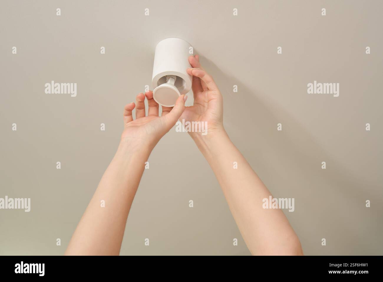 Hands installing or replacing a ceiling light fixture. Home lighting and interior maintenance concept. Stock Photo
