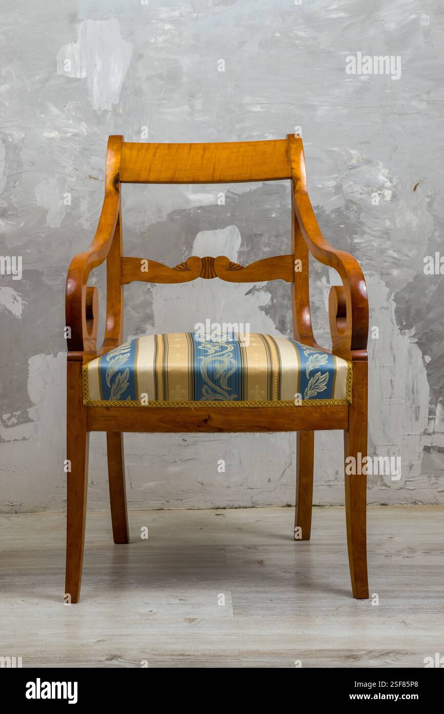 Biedermeier-style armchair in a room setting with a textured wall and ...