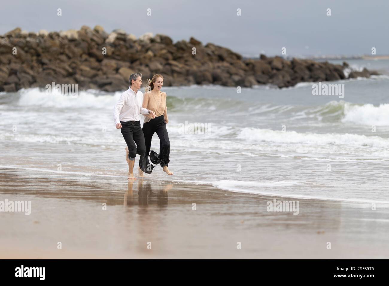 Couple running on the beach holding hands and having fun Stock Photo ...