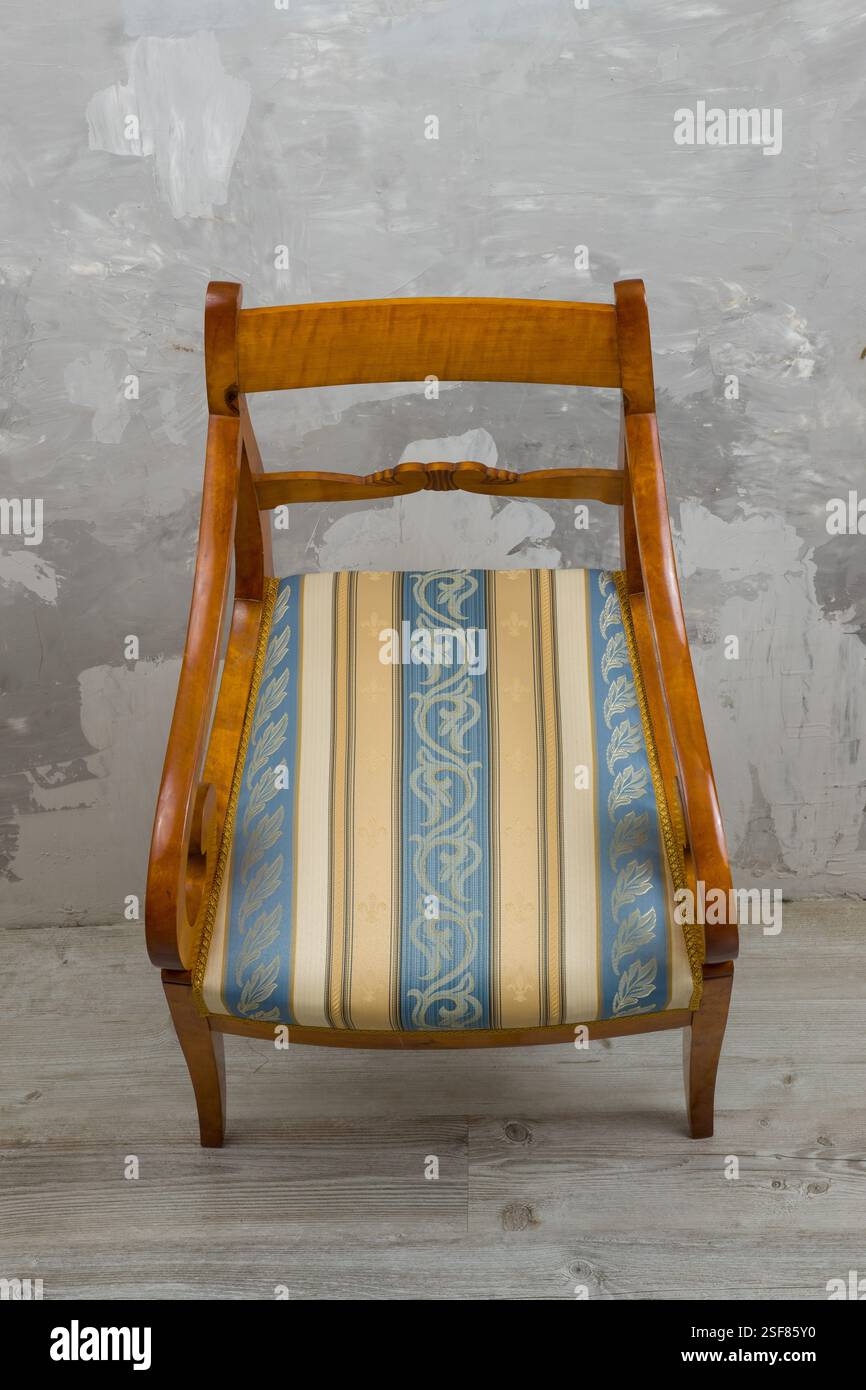 Biedermeier-style armchair in a room setting with a textured wall and ...