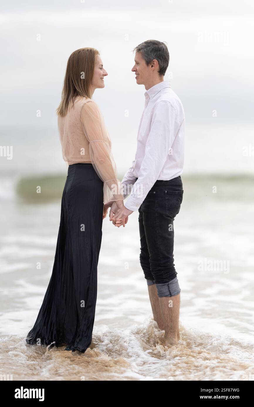 Romantic couple holding hands in the ocean waves Stock Photo - Alamy