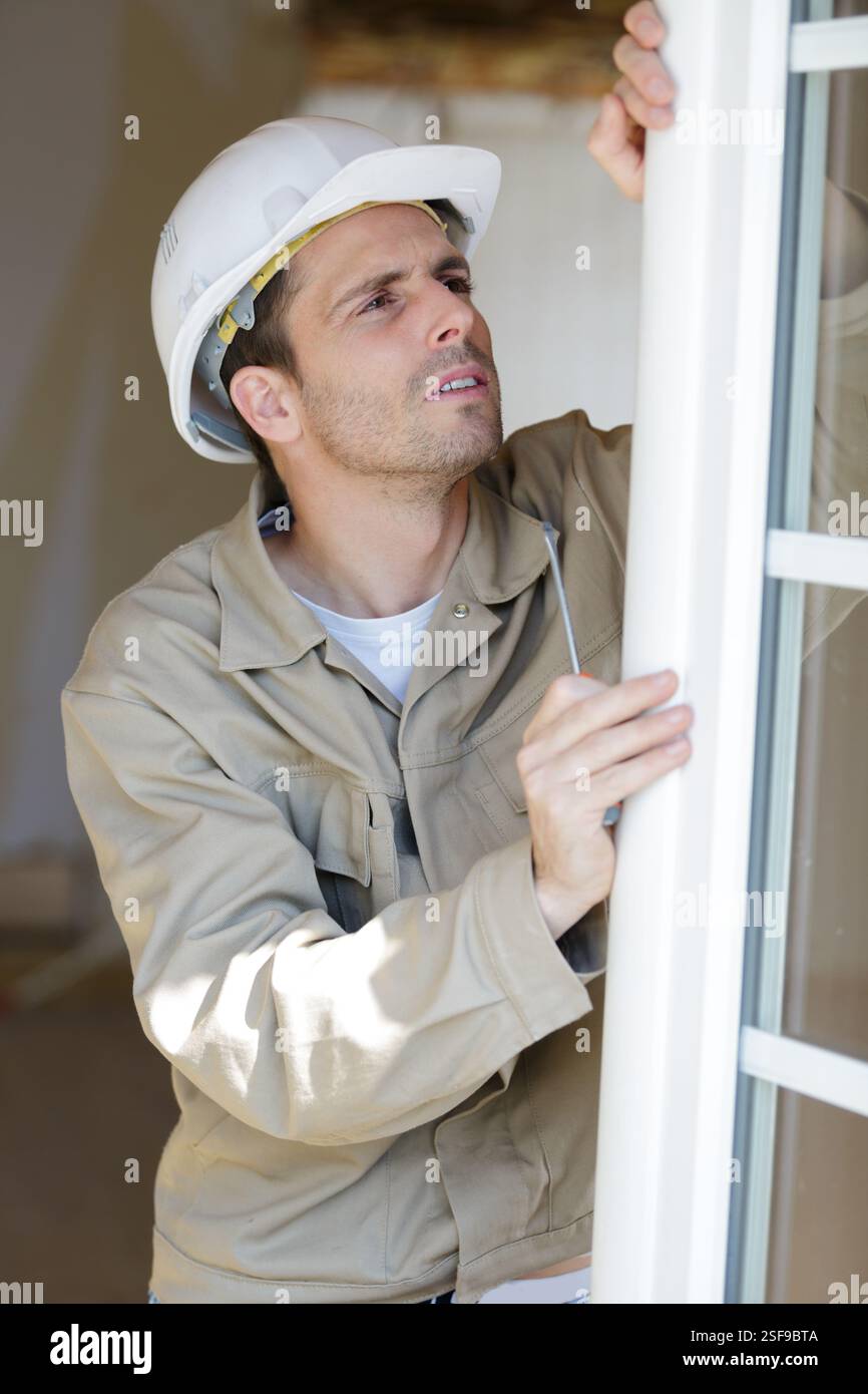 service man installing window with screwdriver Stock Photo