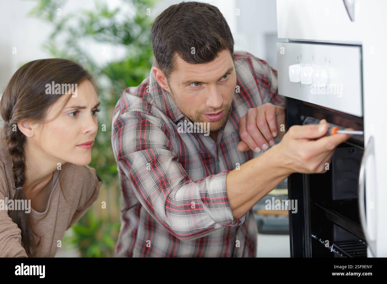 male worker installing oven for repairing in kitchen Stock Photo