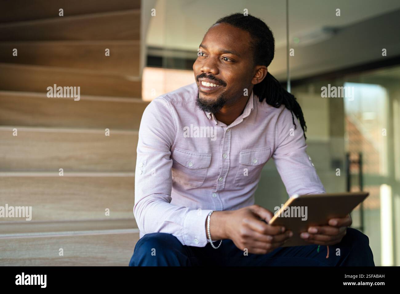 Relaxed smiling african american man holding digital tablet computer using apps Stock Photo