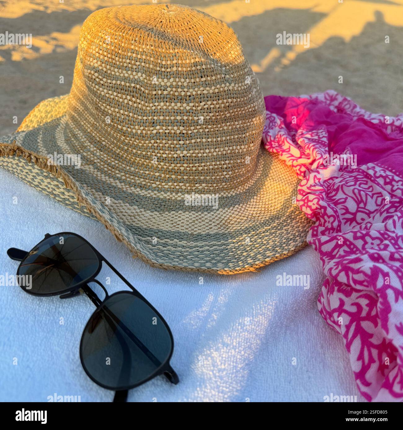 Close-up of a straw sun hat, sunglasses and sarong on a sun lounger on ...