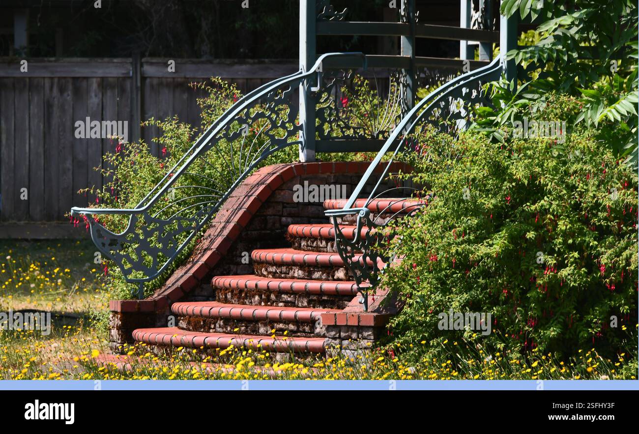 Ornate railings line red brick steps in garden. Decorate iron railing ...