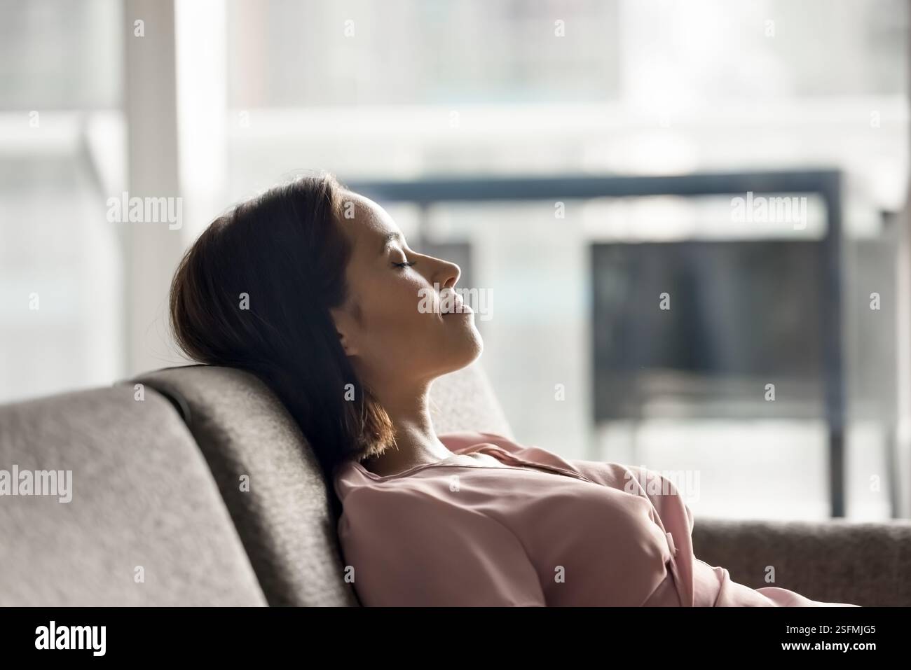 Woman sitting on sofa, leaning back with her eyes closed Stock Photo ...