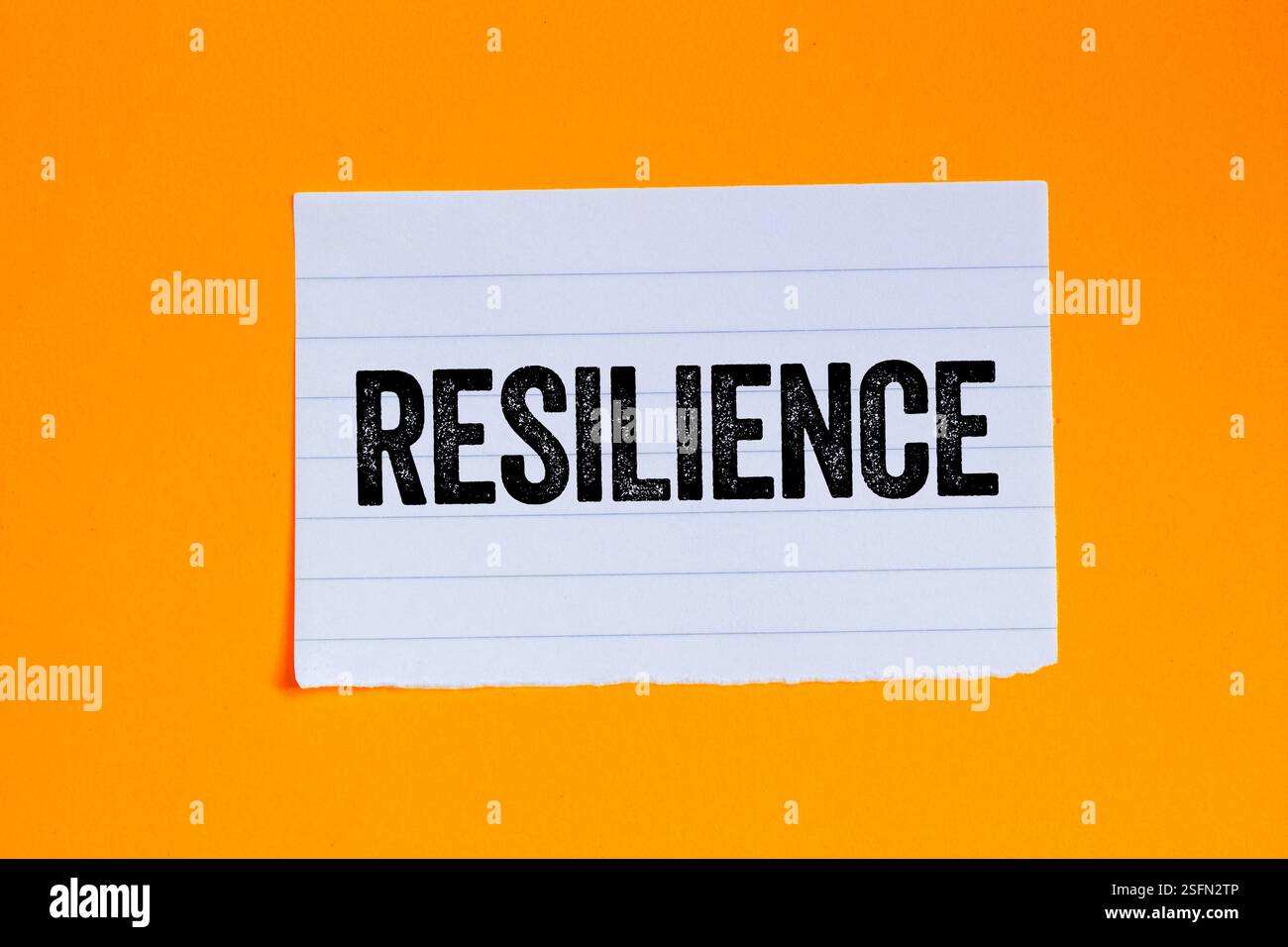 Resilience message written on ripped torn white paper piece on orange ...