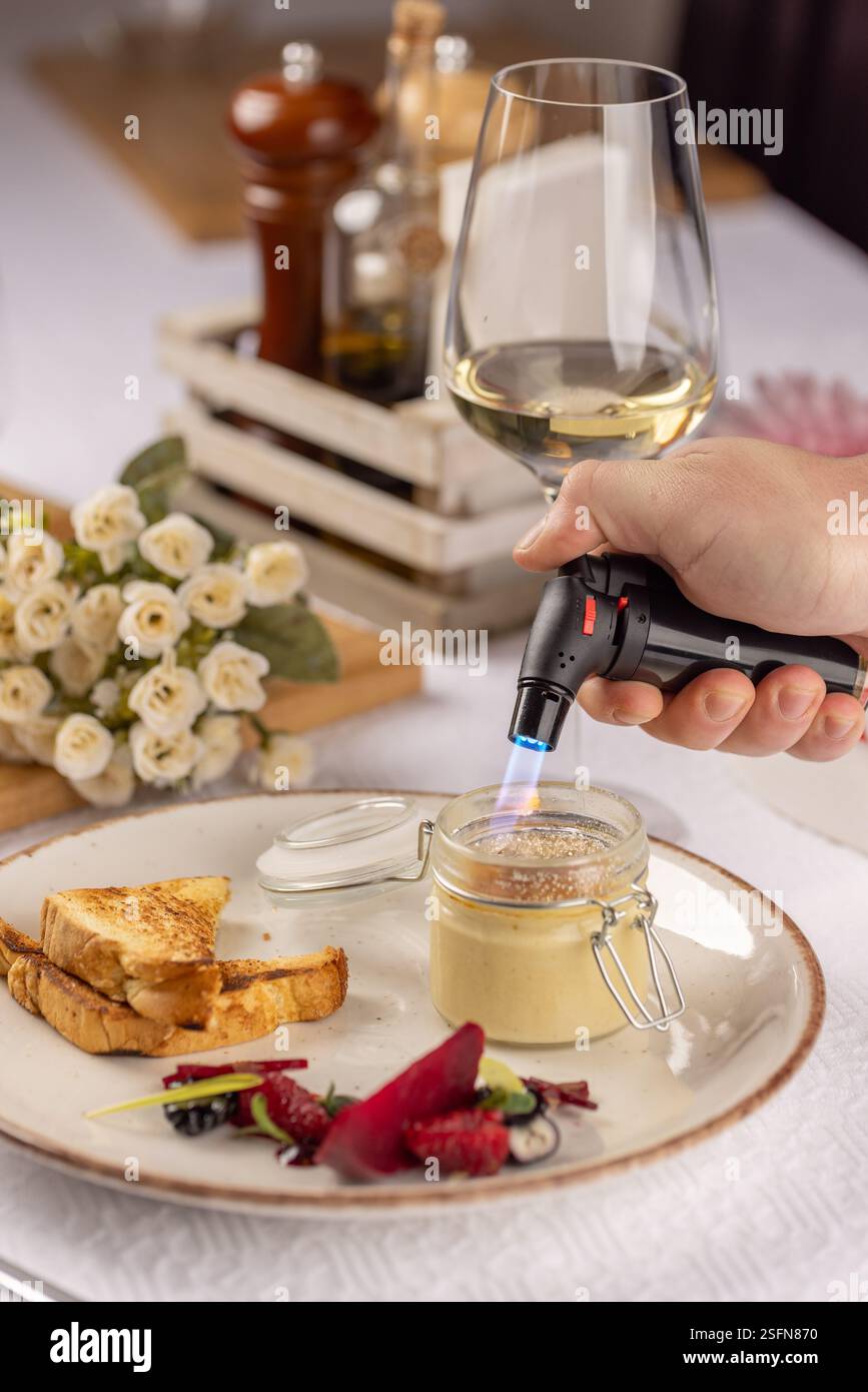 Chef caramelizing creme brulee with a torch, served with toasted bread ...
