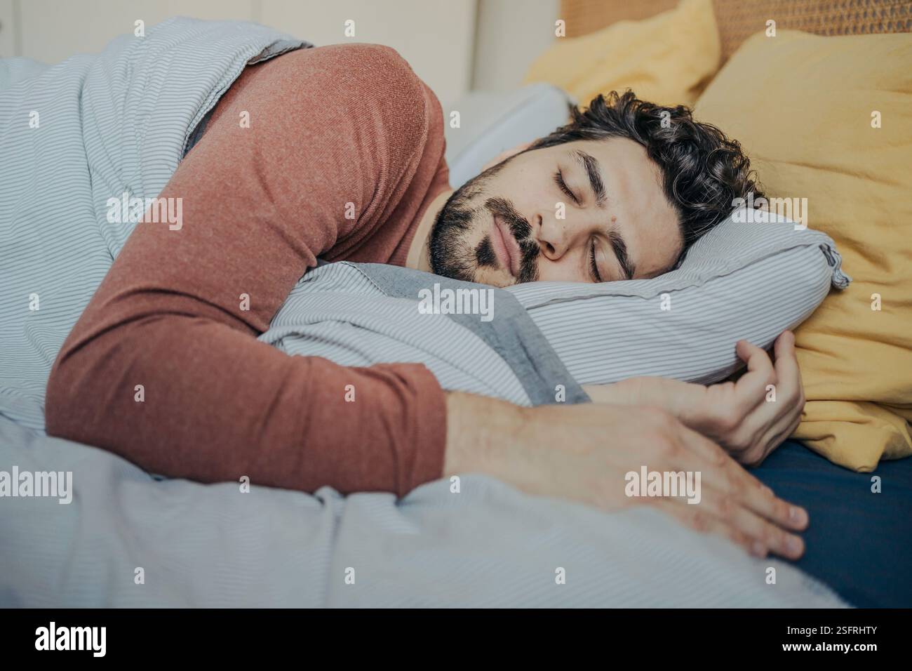 Young handsome middle eastern man sleeping peacefully in his bed. Stock Photo