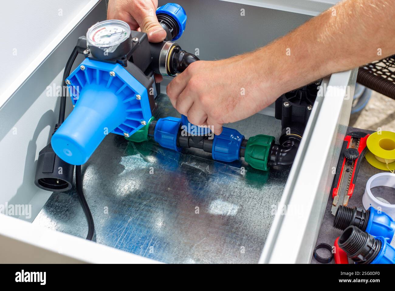 installation of the automatic control unit of the drip irrigation system, arrangement of the automatic control unit elements in a metal box. Stock Photo
