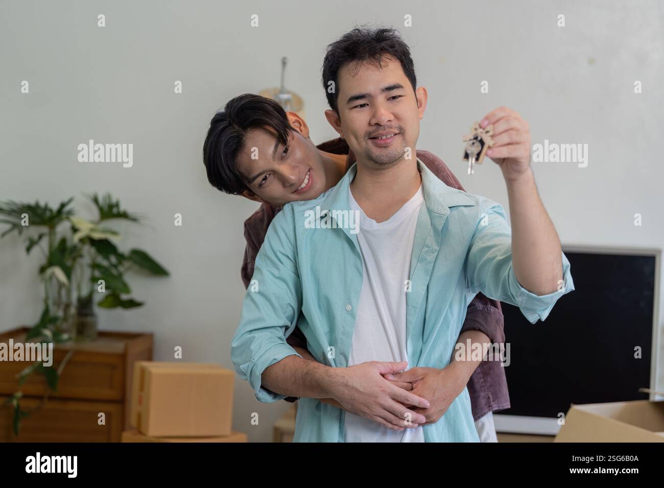 Gay couple celebrating new home, holding house keys together Stock ...