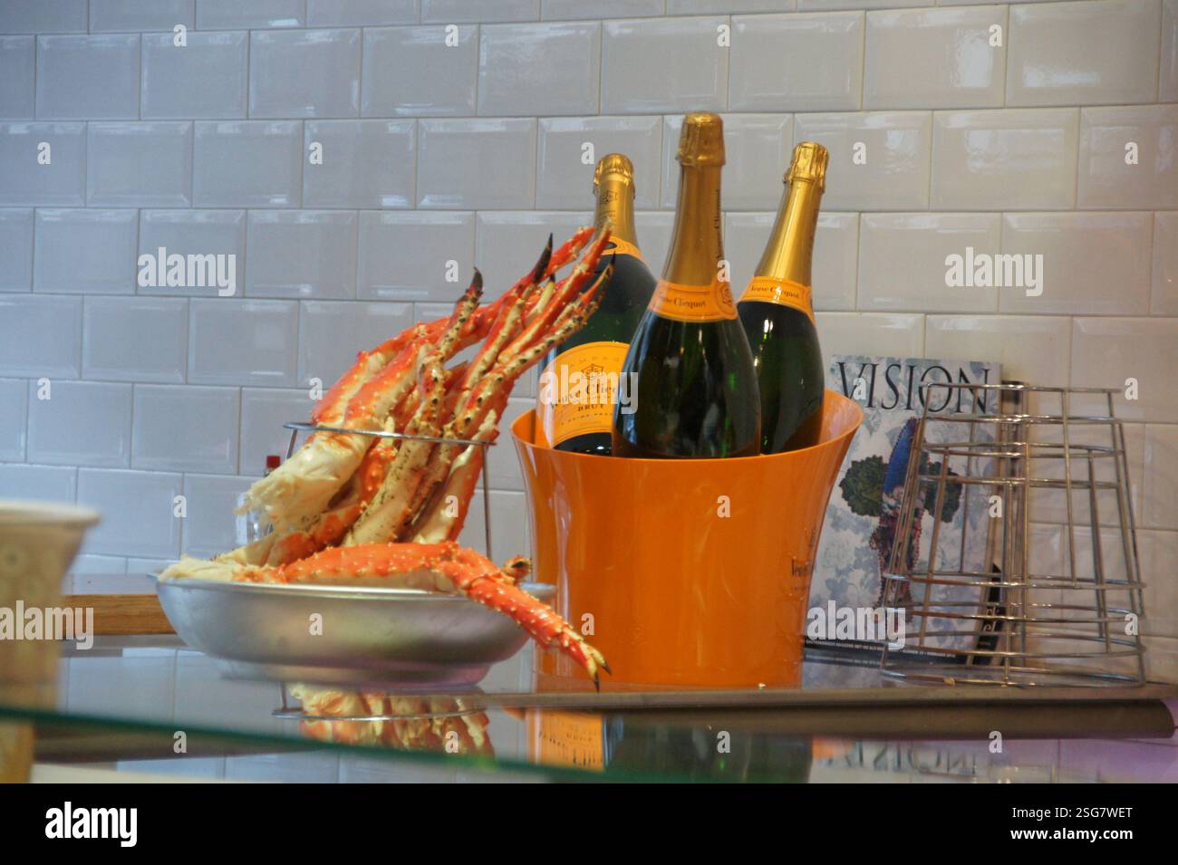 In Amsterdam, two champagne bottles and a bowl of cooked crab legs sit invitingly on a counter. The glistening crab legs hint at a celebratory meal, p Stock Photo