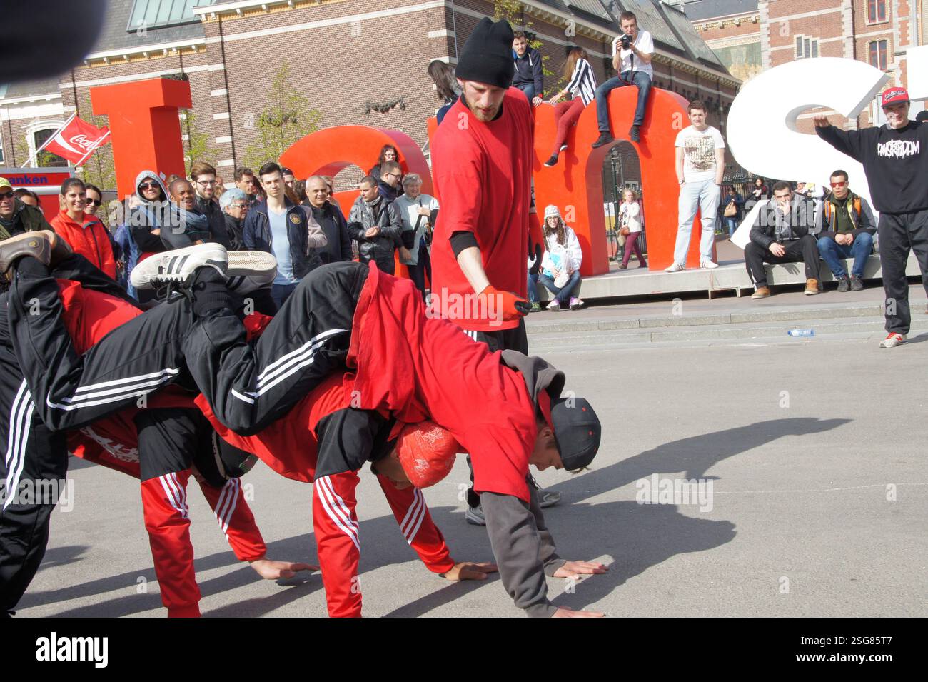 Breakdancers performing dynamic dance moves on the main square, Amsterdam. The dancers showcase their skills, freezing in intricate poses, Amsterdam. Stock Photo