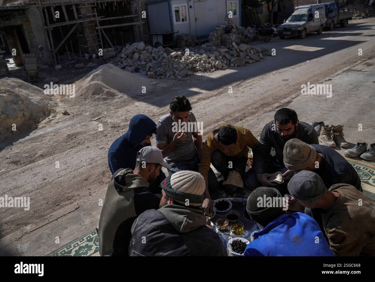 Workers eat breakfast next to a home under construction in the town of ...