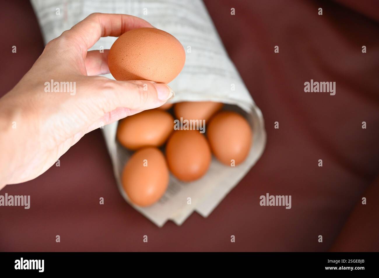 Egg in hand and paper cone on dark background. Stock Photo