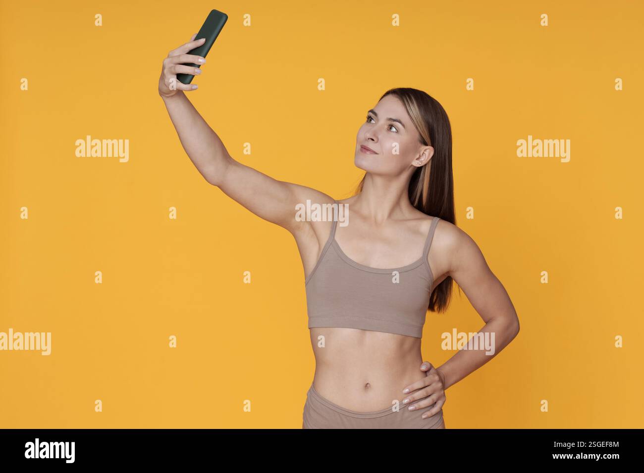 Taking Selfie in Athletic Wear Against Yellow Background Stock Photo