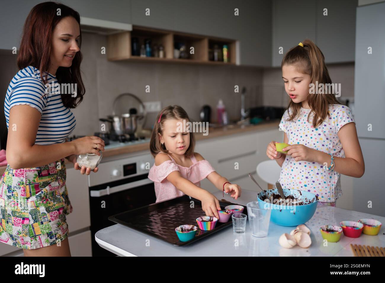 Mother and daughters baking together in modern kitchen Stock Photo