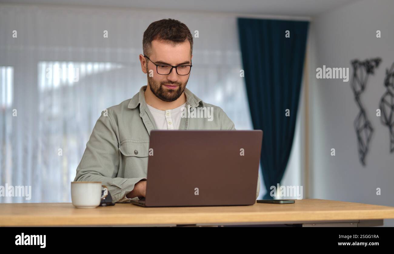A young man using a laptop while working at home. Stock Photo