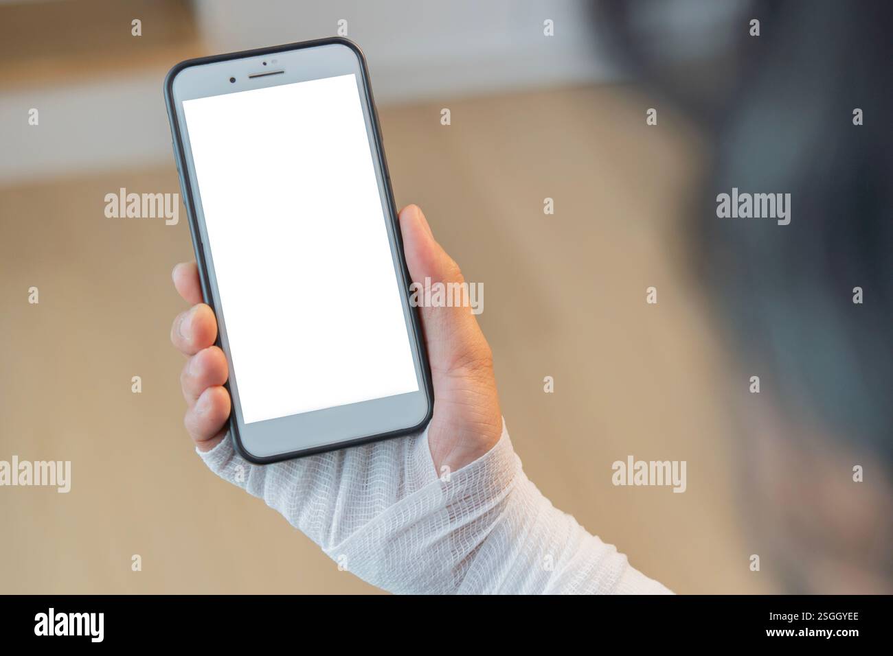 Back view of injured painful hand with bandage and using smart phone with isolate screen. Copy space, selective focus. Stock Photo