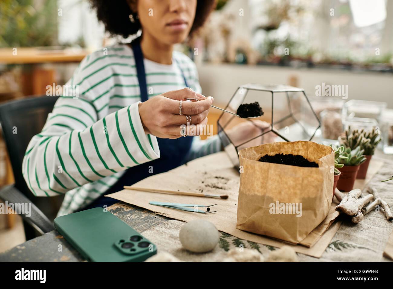 Participant engage in a hands on terrarium workshop, crafting vibrant plants together. Stock Photo