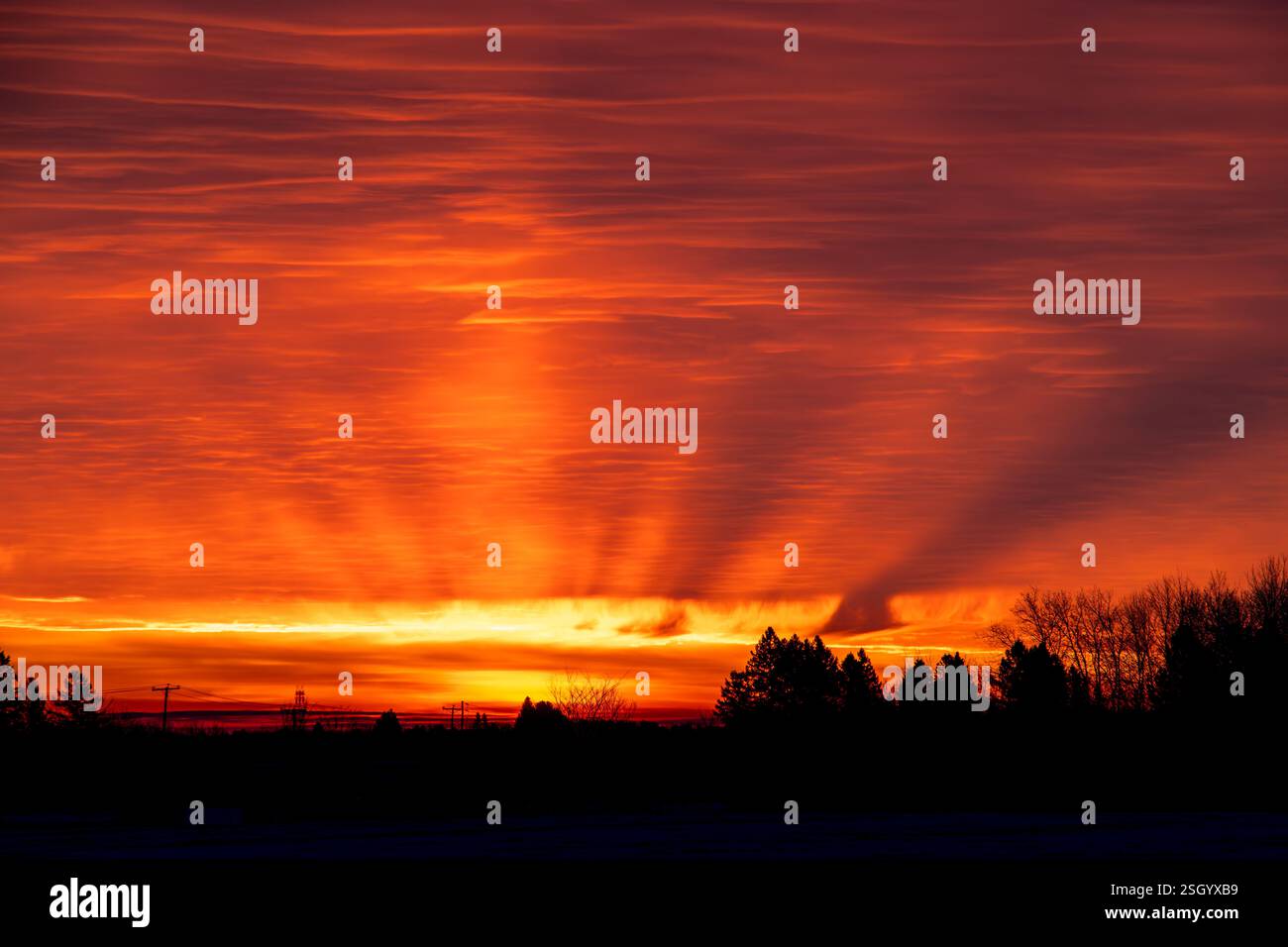 Red sunrise with sun beams coming through the clouds. Winter morning. Stock Photo