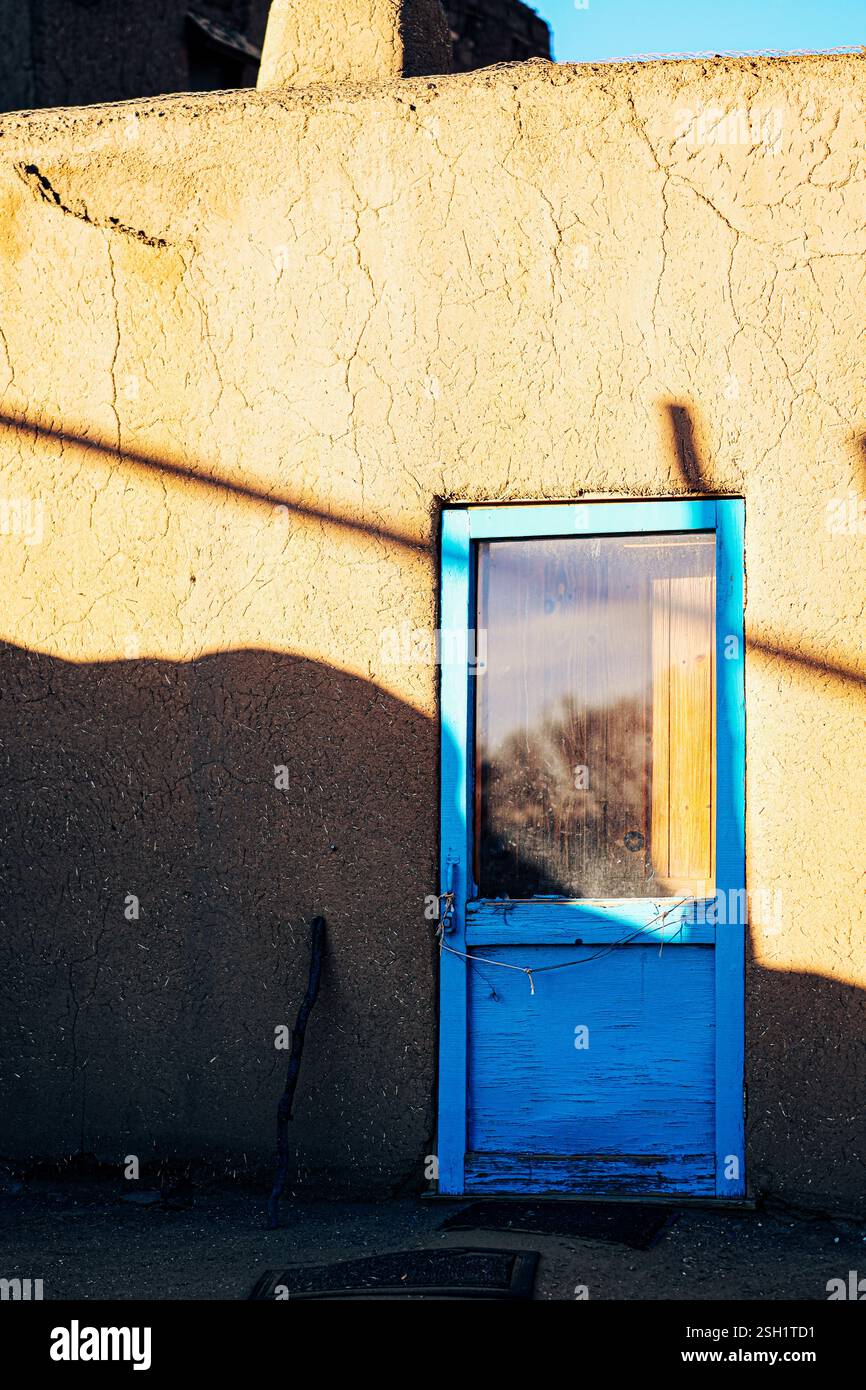 Charming Blue Door on Adobe Wall with Shadows and Textures Stock Photo