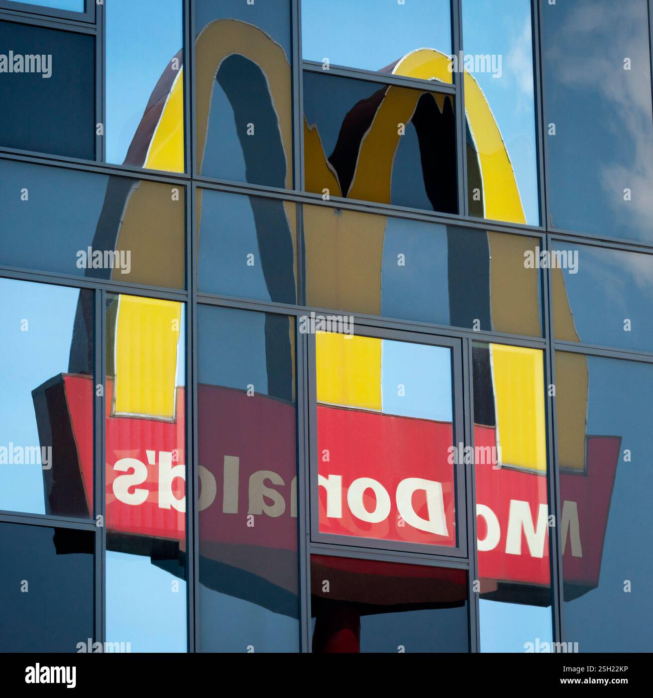McDonald's logo and sign reflection in glass building as unusual uncommon unique view composition Stock Photo
