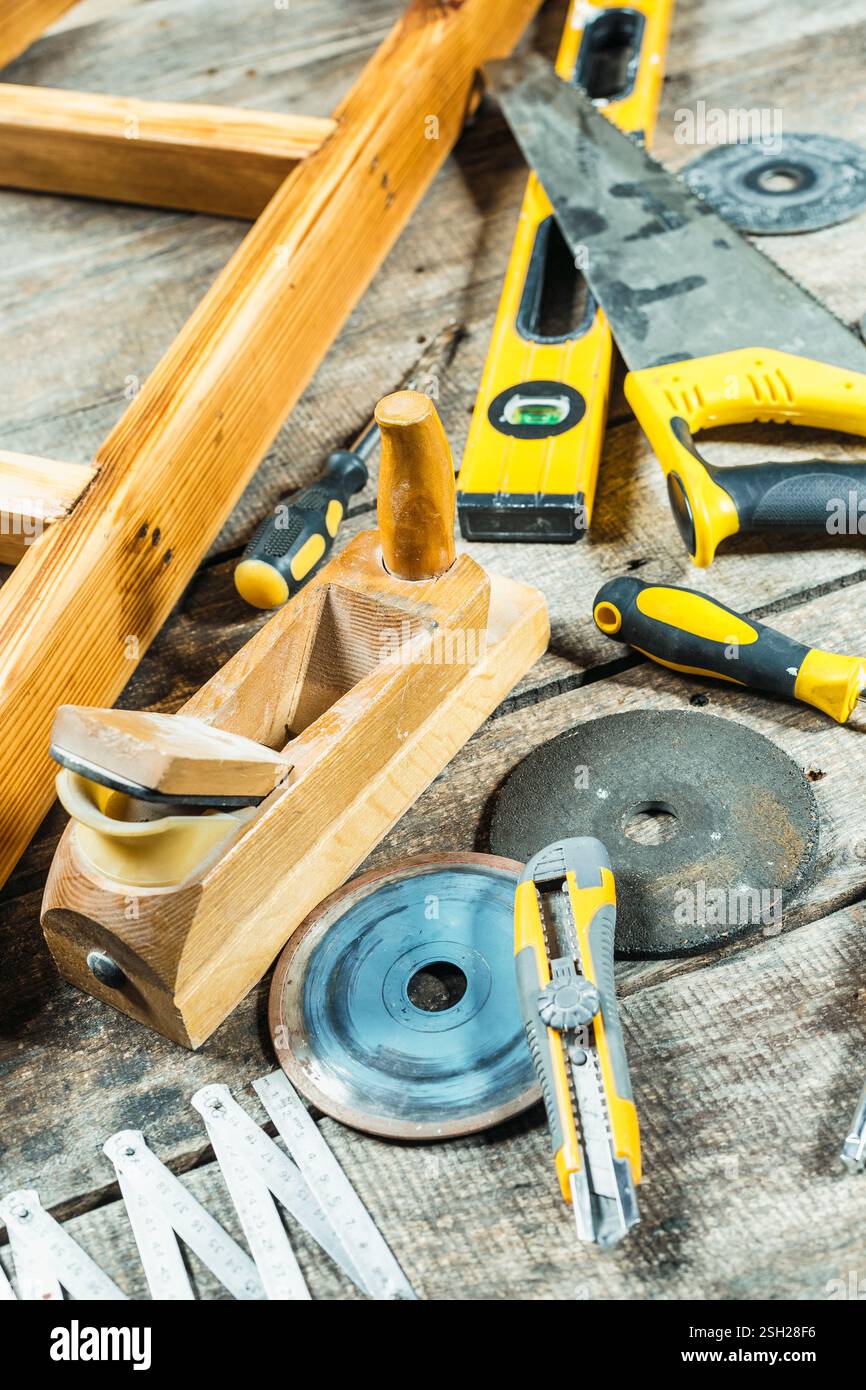 Workspace filled with various hand tools and woodworking equipment on rustic wooden surface Stock Photo
