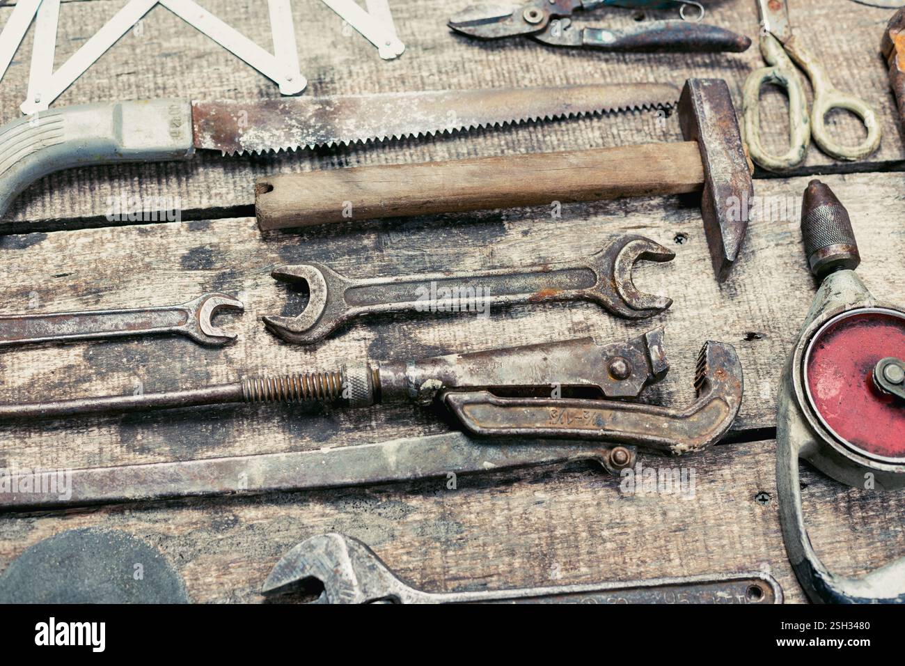 Assorted hand tools displayed on rustic wooden surface in workshop setting during daylight hours Stock Photo