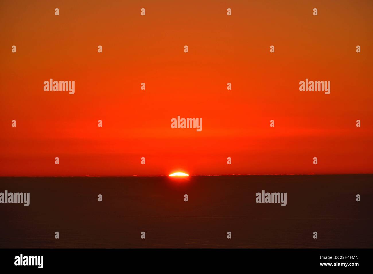 Nearing the end of the journey, the sun hides behind the horizon line Stock Photo