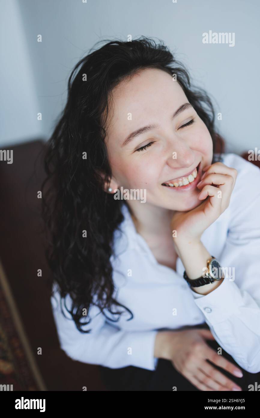 A cheerful young woman with beautiful curly hair beams with a bright smile, radiating genuine happiness and positivity Stock Photo