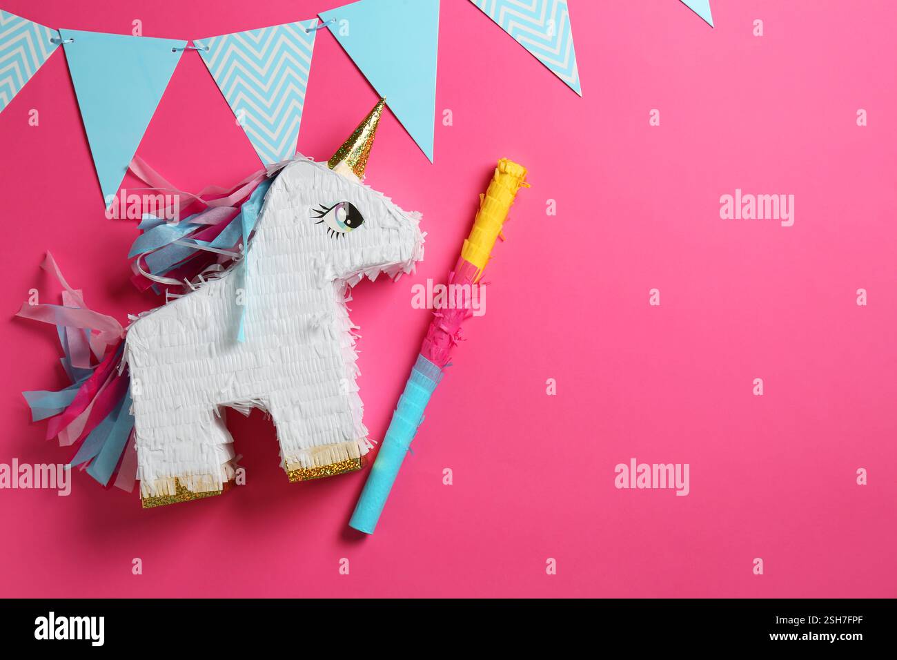 Bright pinata in shape of unicorn and party accessories on pink ...