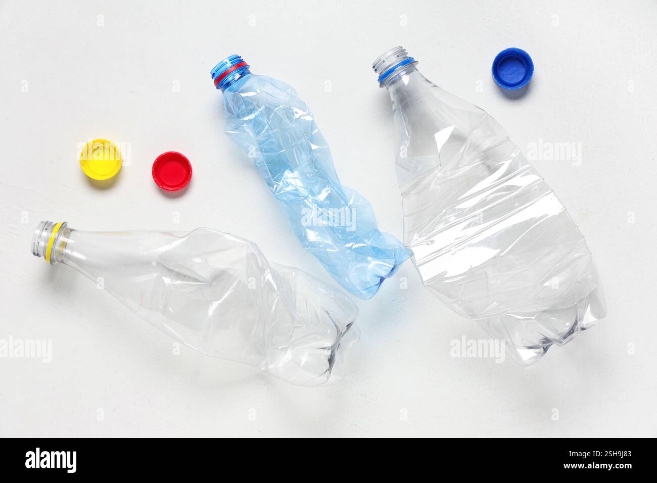 Crumpled plastic bottles with caps on white background Stock Photo - Alamy