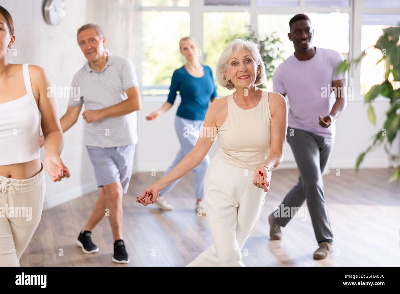 Senior woman learning dynamic dances with people of different ages Stock Photo